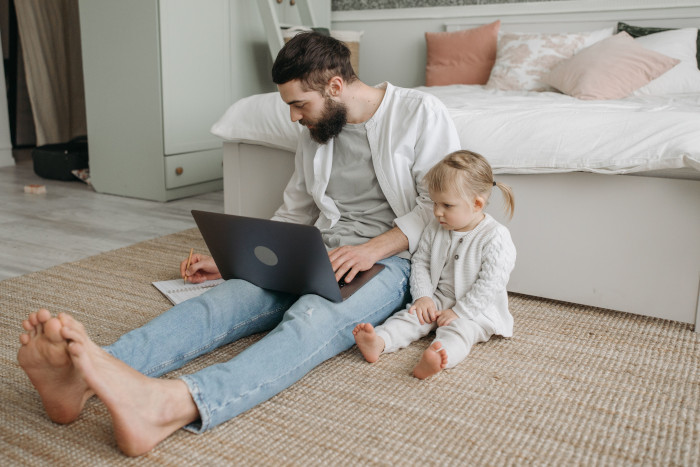 Father with laptop and daughter in bedroom demonstrating home lifestyle and remote work balance.