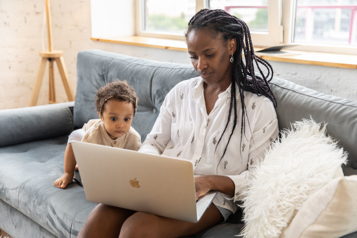 Mother and baby sitting on the sofa using a laptop together indoors